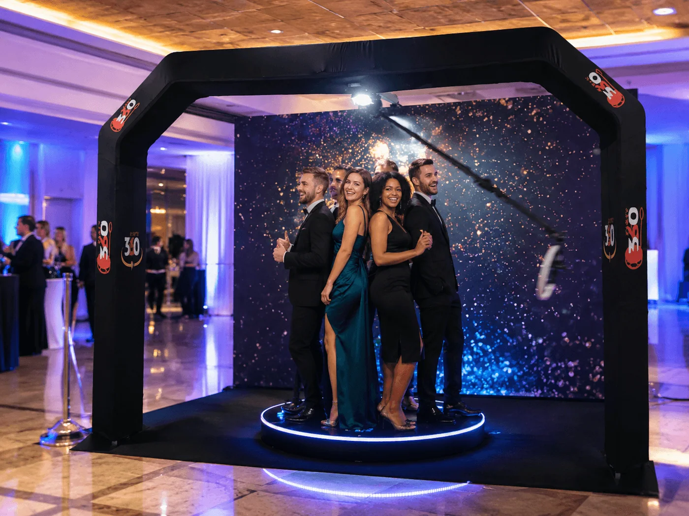 360 photo booth in action at a corporate event, overhead camera arm rotating around guests on illuminated platform